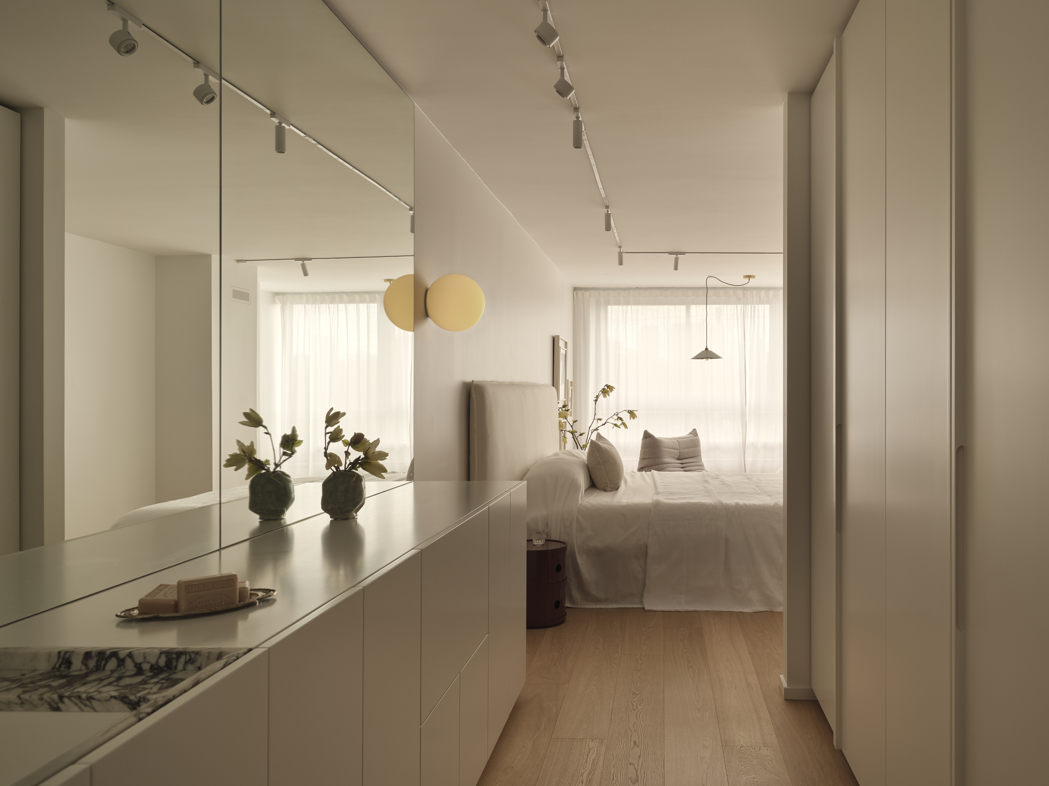 Primary bedroom with full mirrored wall and white millwork dresser