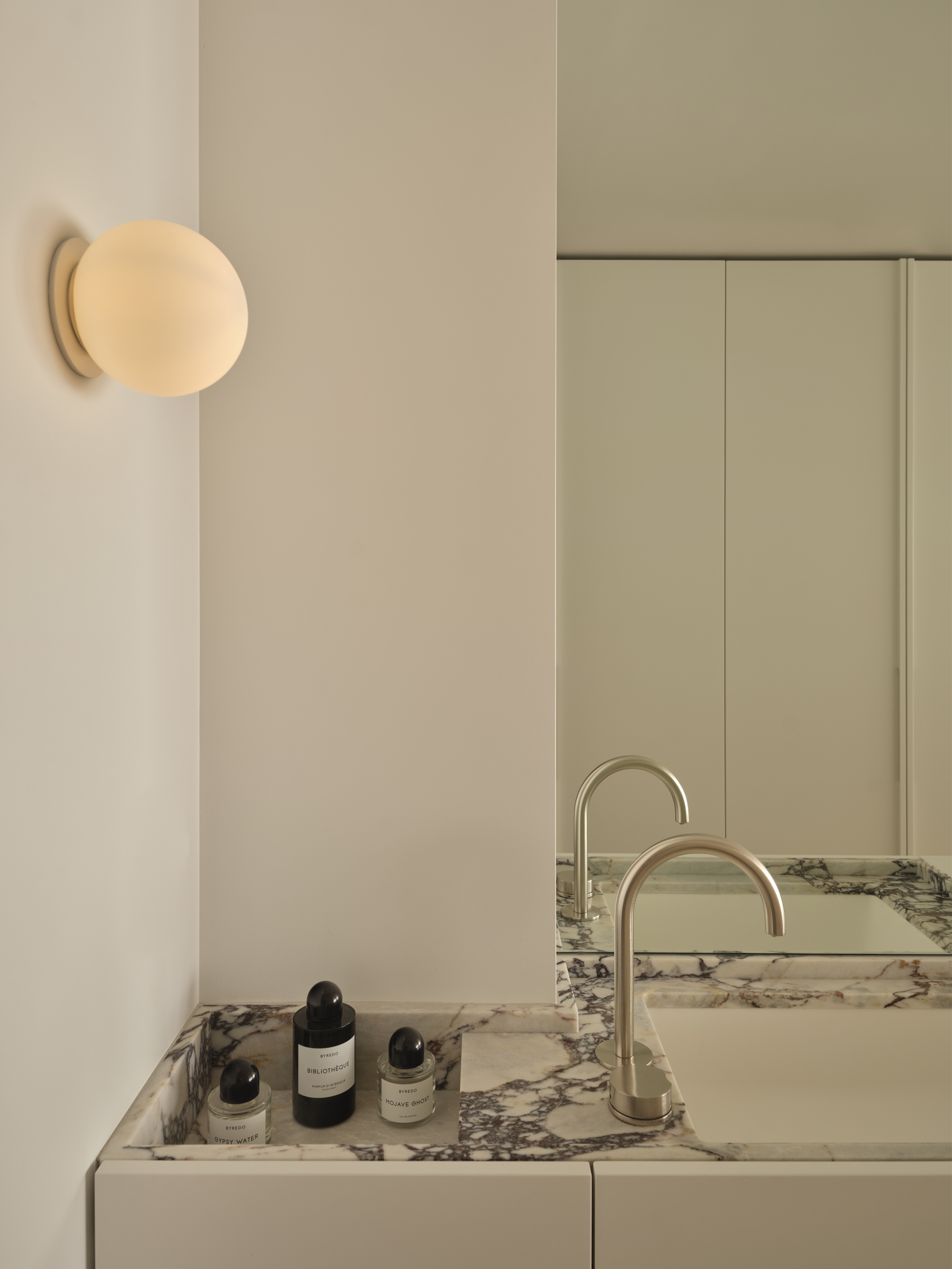 Vanity detail with Calacatta Viola marble countertop and opal glass sconce