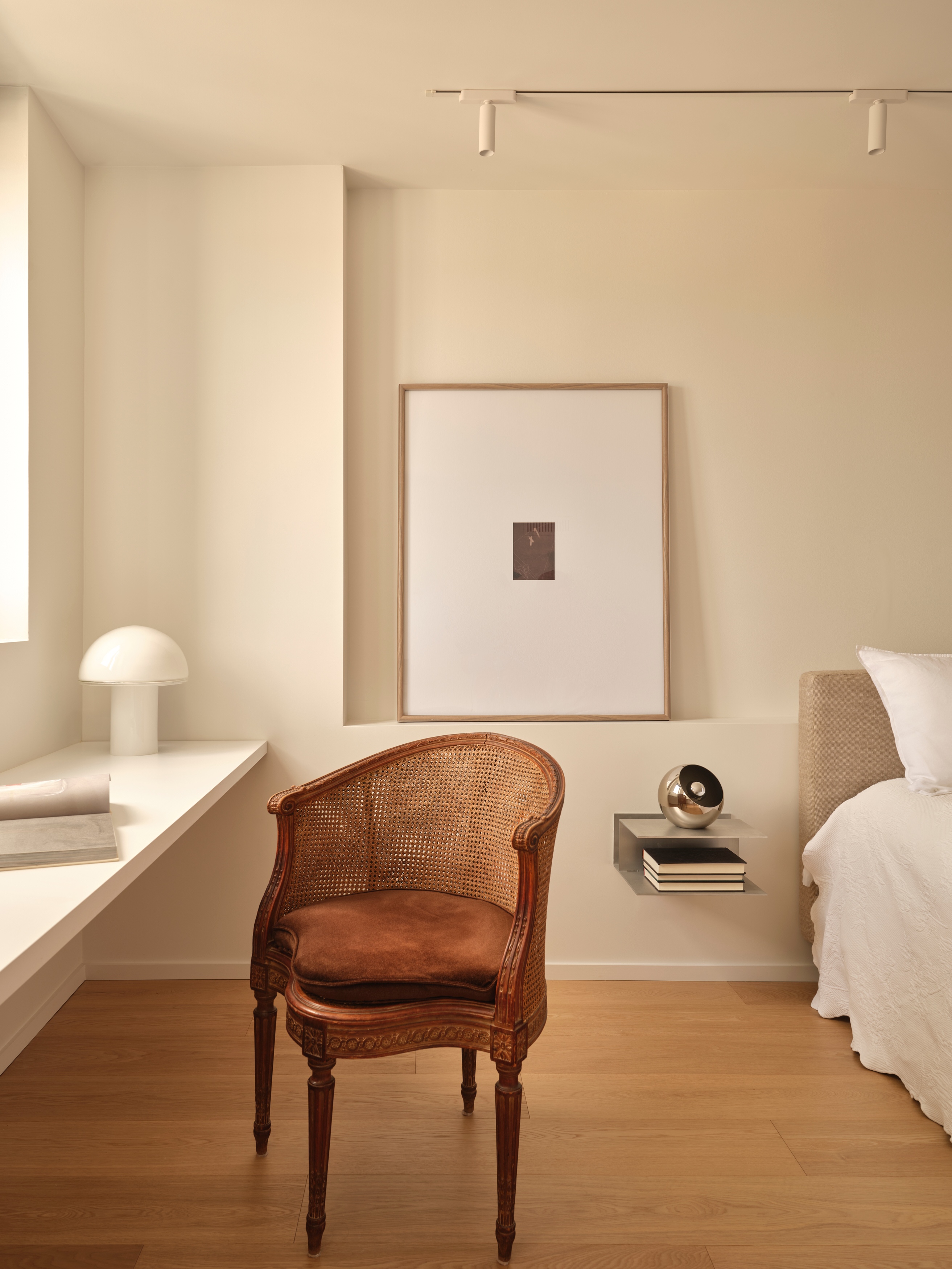 Bedroom corner with floating white desk, mushroom lamp, and vintage cane chair