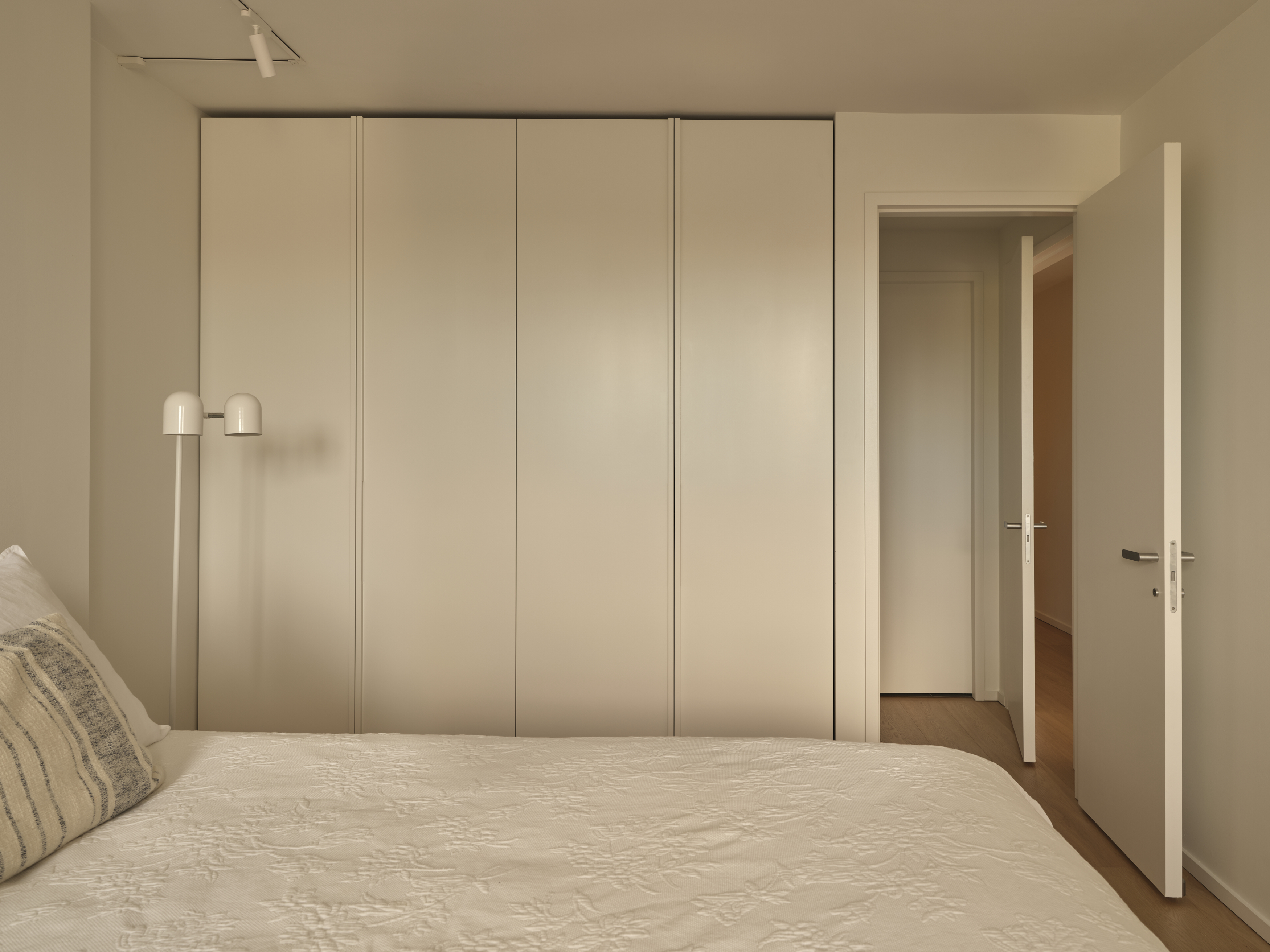 Bedroom with tall cream wardrobe wall and double-headed sconce