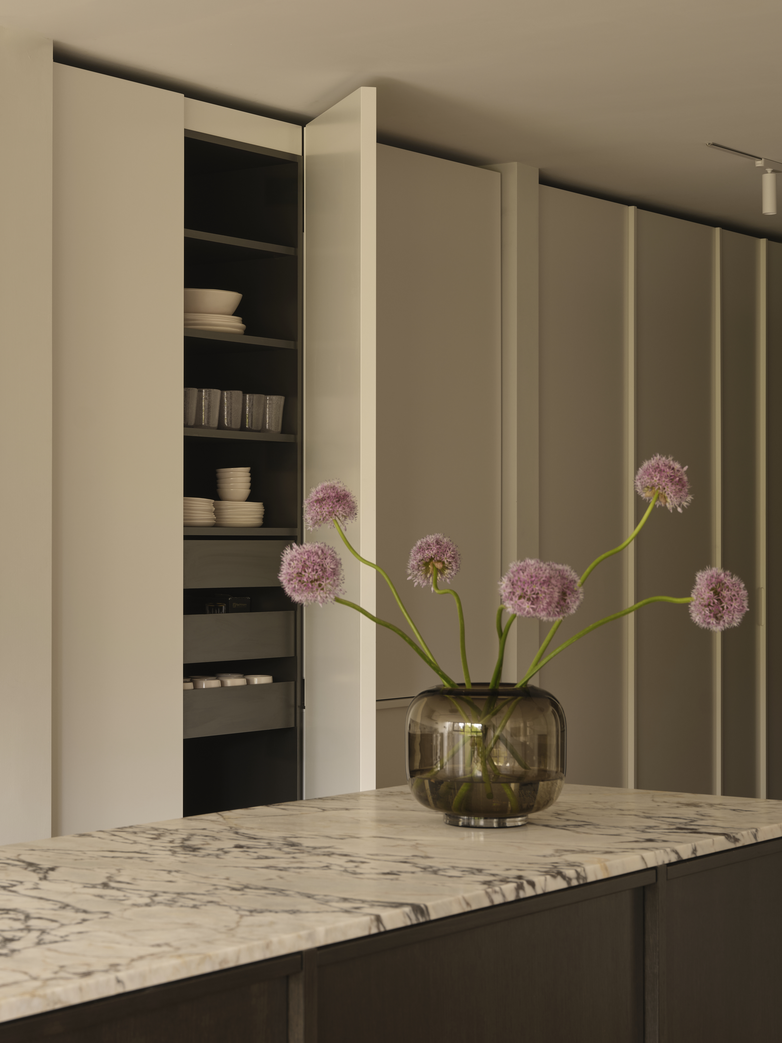 Kitchen island detail with Calacatta Viola marble and open pantry of dishware
