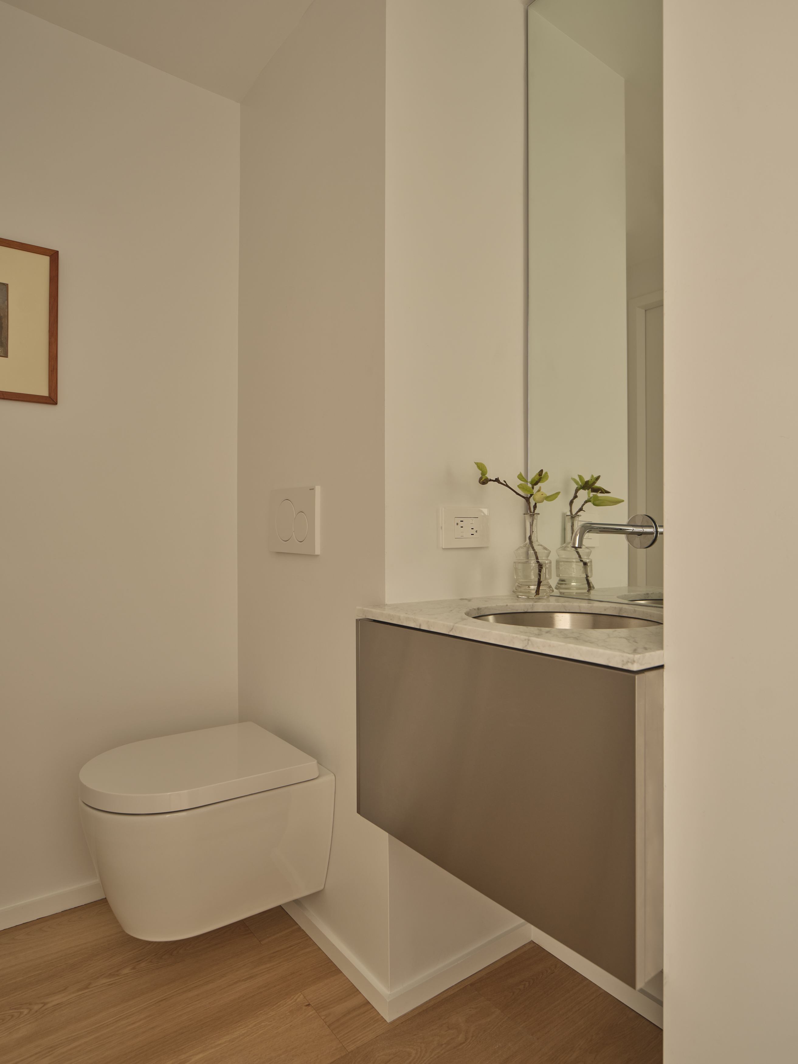 Powder room with wall-hung toilet, floating stainless vanity, and tall mirror