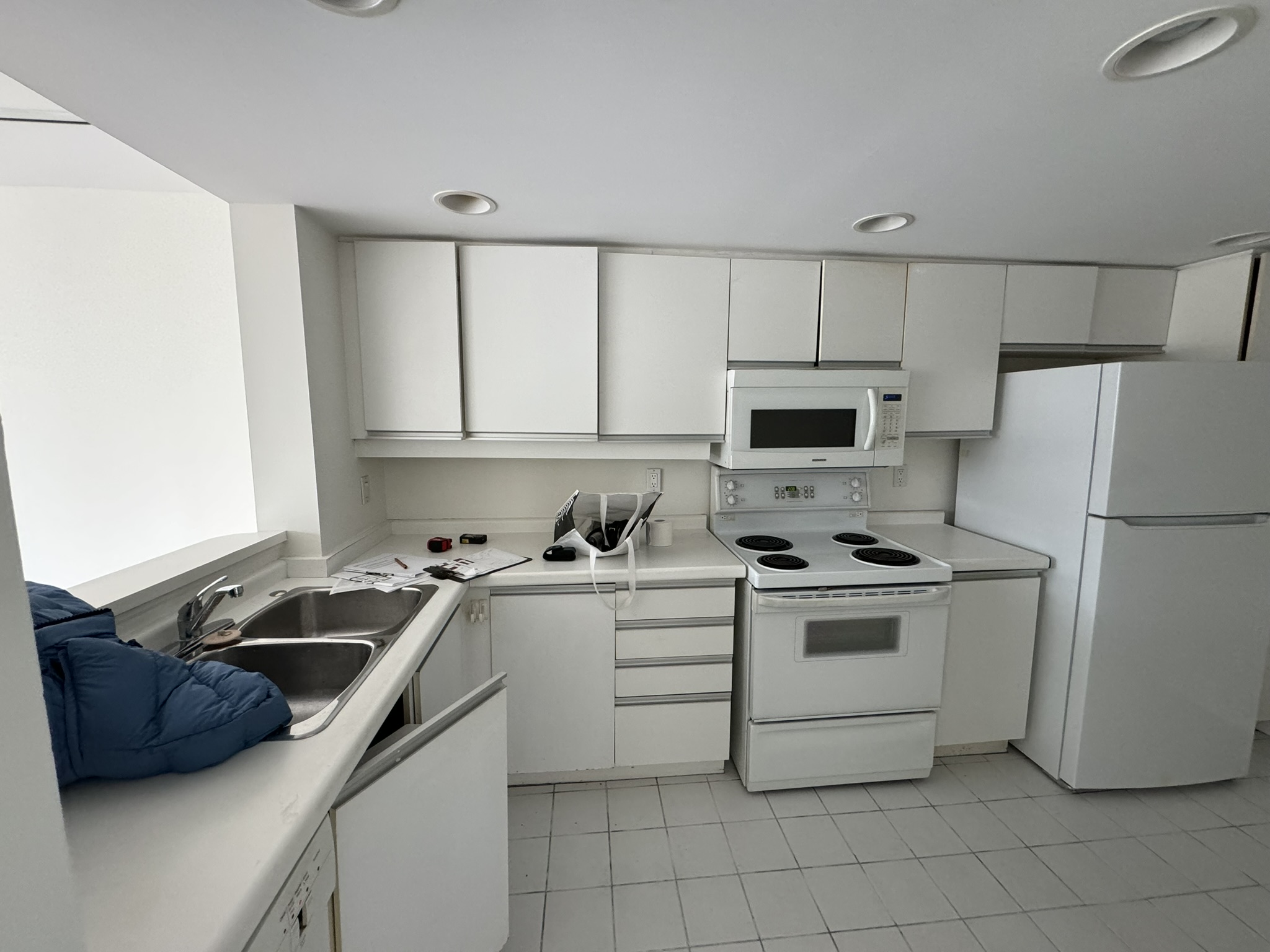 Original closed-off kitchen with dated white laminate cabinets before renovation